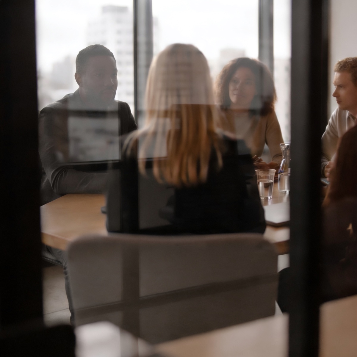 Four people in conversation around a table by a window